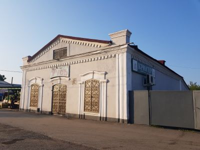 Каменный дом середины ХIХ века с коваными фигурными воротами с художественными литыми накладками, ныне магазин промышленных товаров