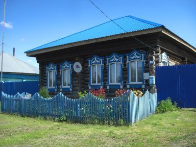 Деревянный дом начала ХХ века с наличниками, воротами, украшенными богатой объемной резьбой на мотив "полотенца"