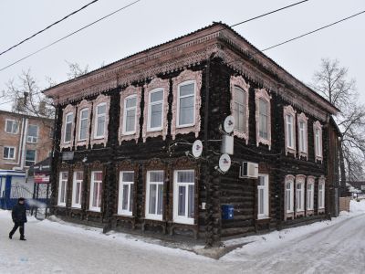 Двухэтажное деревянное здание начала XX века, украшенное обильной резьбой, ныне жилой дом